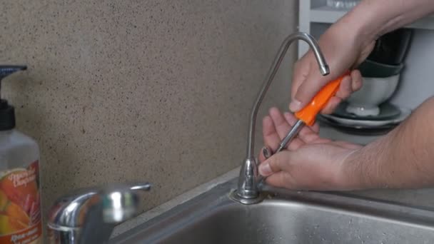 Sanitair reparatie van waterlekken. Handen van een man die een kraan repareert in de keuken in zijn appartement — Stockvideo