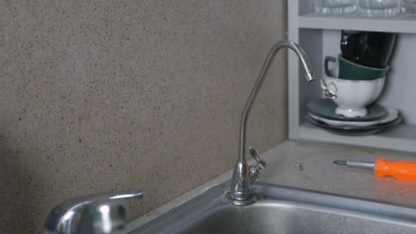 Reparatur von Wasserleitungen nach Wasserlecks. Hände eines Mannes, der in seiner Wohnung einen Wasserhahn in der Küche repariert — Stockvideo