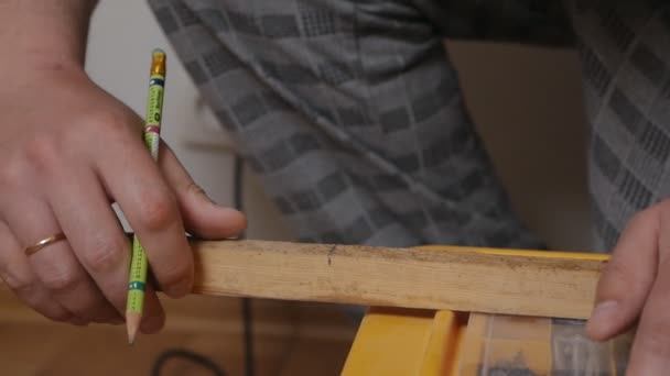 Un hombre calvo hace reparaciones en una casa, apartamento, trabaja con un árbol, un bloque de madera, mide el tamaño de un bloque de madera. Construcción de viviendas. Diseño de interiores. Concepto de actualización y mejora — Vídeo de stock