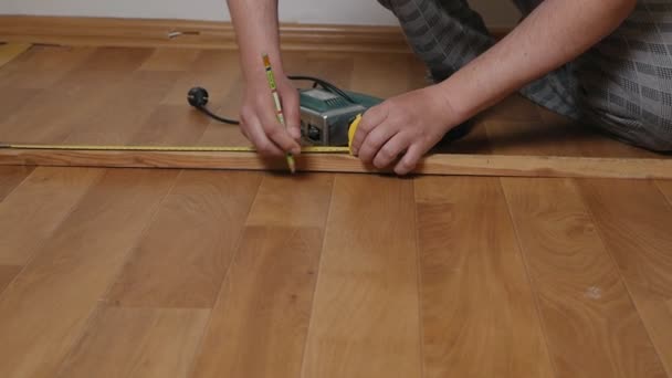 Ein Mann mit Glatze repariert in einem Haus, einer Wohnung, arbeitet mit einem Baum, einem Holzklotz, misst die Größe eines Holzklotzes. Hausbau. Innenarchitektur. Modernisierungs- und Verbesserungskonzept — Stockvideo