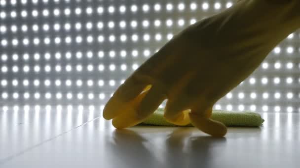 Cleaning the table surface at home. Hand in gloves and a towel rubs a table against the background of lanterns — Stock Video