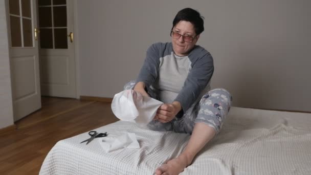 Una mujer en casa hace el procedimiento de pelar los pies con calcetines especiales para la pedicura. Pedicura SPA y cuidado de pies y uñas — Vídeos de Stock