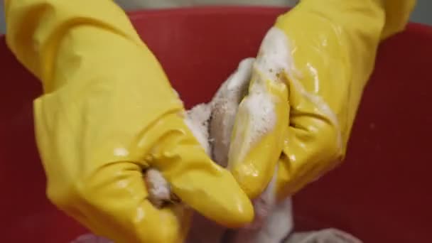 En kvinna tvättar kläder, en handduk i ett handfat med tvättmedel i handskar. Hur man tvättar bort färg — Stockvideo