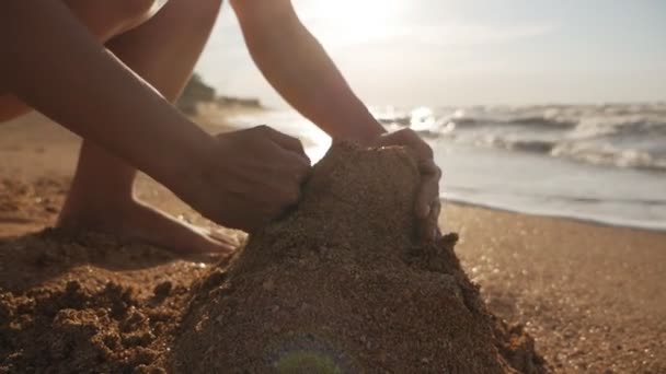Atrakcyjna młoda kobieta budująca zamek z piasku na plaży o zachodzie słońca — Wideo stockowe