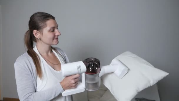 一个女人正在用一个现代的无绳真空吸尘器用一个特殊的附件，特写来清洁枕头。无绳真空吸尘器干洗概念 — 图库视频影像