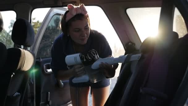 Молодая женщина делает еженедельную уборку семейного автомобиля с пылесосом, уборка автомобиля — стоковое видео