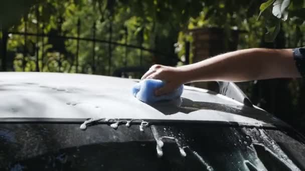 Una mano di uomo in estate strofina il tetto della sua auto nel cortile di una casa sulla strada, lava l'auto, pulisce lo sporco dalla superficie — Video Stock