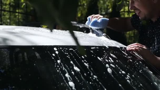 Человек с губкой мыть крышу автомобиля автомобиля во дворе сада — стоковое видео