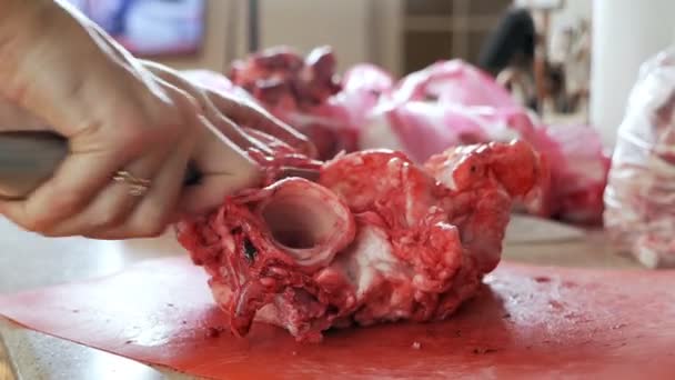 Ludzkie ręce używają noża rzeźniczego, który jest używany do gotowania i krojenia mięsa. Ręce pokrojone nożem mięso, wieprzowina pokryta krwią — Wideo stockowe