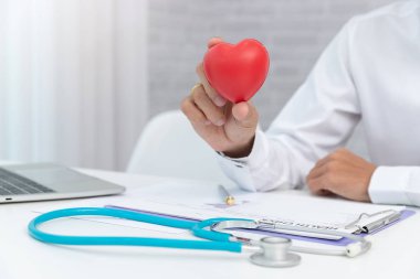 Sağlık ve tıp kavramı, klinikte kırmızı kalp topu tutan doktor.
