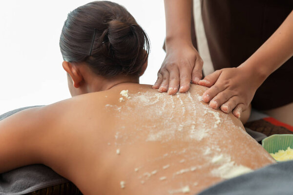 Asian woman enjoying a salt scrub massage at spa.