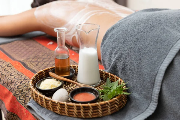 Asian woman enjoying a salt scrub massage at spa.