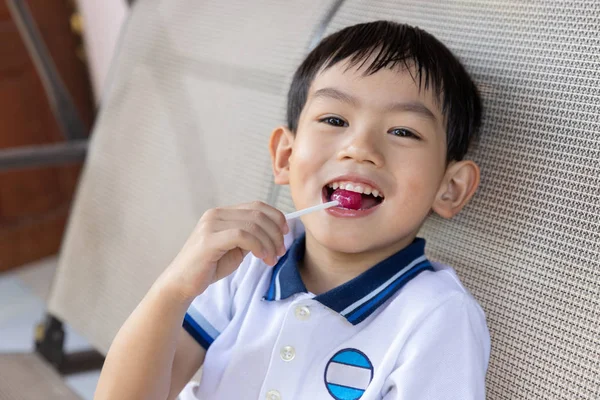 把吃棒棒糖的亚洲小男孩关起来 — 图库照片