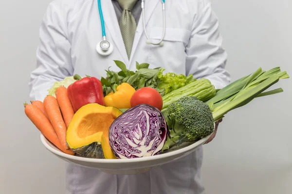 Healthy and nutrition concept. Doctor holding bowl of fresh fruits and vegetables.