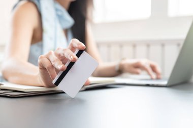 Kafedeki bilgisayar laptopuyla alışveriş için kredi kartı tutan serbest çalışan bir kadın..