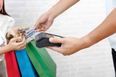 Kredi kartı ödeme servisi. Alışveriş çantası taşıyan ve alışveriş merkezinde sipariş vermek için kredi kartı kullanan bir kadın.
