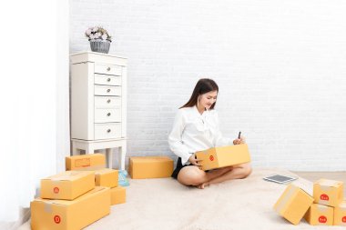 Genç kız siparişi kontrol ettikten sonra müşteriye mal göndermeye hazırlan, evde çalış..