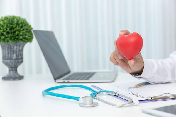 Здравоохранение и медицинская концепция, доктор, держащий красный сердечный шар в клинике
.