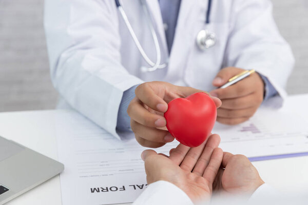 Здравоохранение и медицинская концепция, доктор, держащий красный сердечный шар в клинике
.