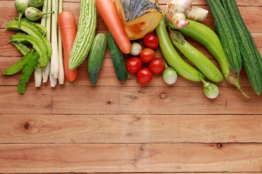 Tayland mutfağı. Ahşap zemin üzerinde boş sayfa ve kalem bulunan çeşitli sebzeler, baharatlar ve malzemeler. Kopyalama alanı olan üst görünüm