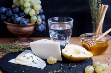 Keçi peyniri üzüm, bal ve karanlık bir arka plan üzerinde armut ile servis