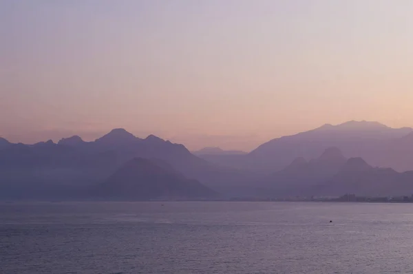 Mountains in a blue haze and sunset over the sea