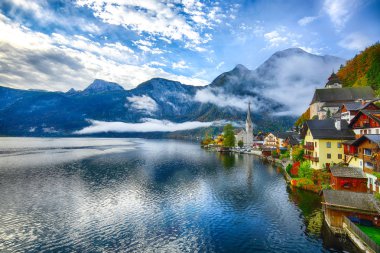 Sisli sonbahar gün doğarken Hallstattersee gölde yansıtan ünlü Hallstatt lakeside kasaba. Yer: resort köyü Hallstatt, Salzkammergut bölge, Avusturya, Alpler. Europe... Yer: resort köyü Hallstatt, Salzkammergut bölge, Avusturya, Alpler. EUR