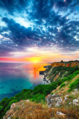 Cape Fiolent 'te gün batımında çimenler ve kayalar ön planda. Kırım