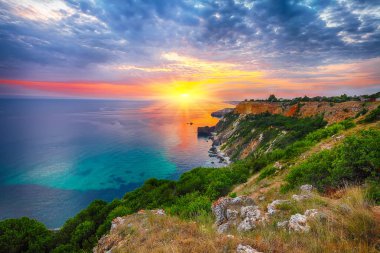 Cape Fiolent 'te gün batımında çimenler ve kayalar ön planda. Kırım