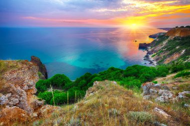 Cape Fiolent 'te gün batımında çimenler ve kayalar ön planda. Kırım