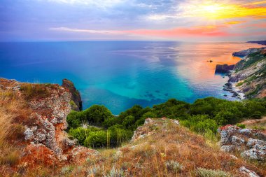 Cape Fiolent 'te gün batımında çimenler ve kayalar ön planda. Kırım