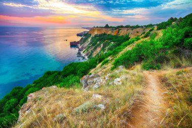 Cape Fiolent 'te gün batımında çimenler ve kayalar ön planda. Kırım