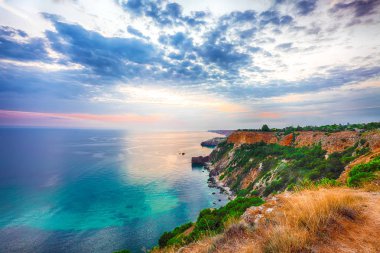 Cape Fiolent 'te gün batımında çimenler ve kayalar ön planda. Kırım