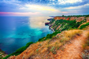 Cape Fiolent 'te gün batımında çimenler ve kayalar ön planda. Kırım