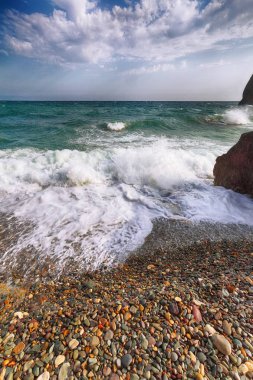 Kıyıda çökmesini ve sahil çakıl akan deniz dalgaları. Kayalık deniz kıyısı