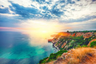 Cape Fiolent 'te gün batımında çimenler ve kayalar ön planda. Kırım