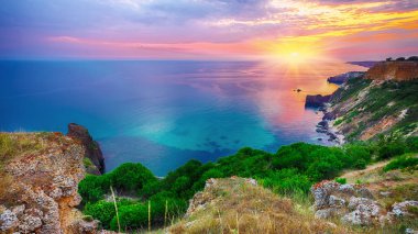 Cape Fiolent 'te gün batımında çimenler ve kayalar ön planda. Kırım