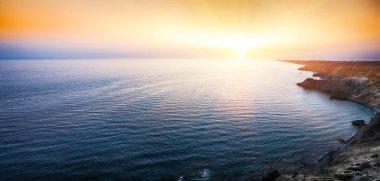 Cape Fiolent dramatik günbatımında kayalar ve ön plan çim. Crimea