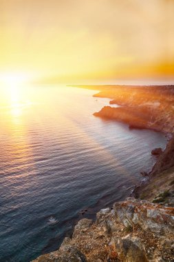 Cape Fiolent dramatik günbatımında kayalar ve ön plan çim. Crimea