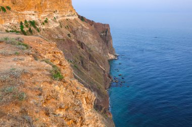 Cape Fiolent dramatik günbatımında kayalar ve ön plan çim. Crimea