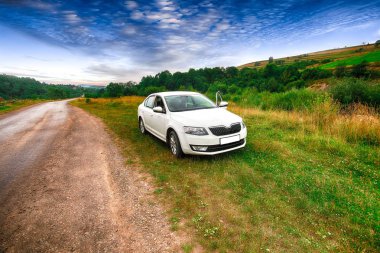 Bir araba ön bakış doğa arka plan üzerinde. Dramatik gökyüzü günbatımı. Kötü yol