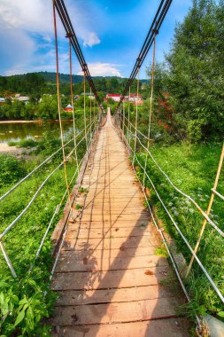 Ahşap asma köprü Nehri Karpat Dağları'nda. dramatik mavi gökyüzü
