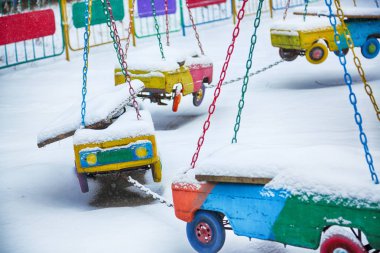 Kış zamanında terk edilmiş atlıkarınca. Kış günü boş çocuk oyun alanı. Çocuk arabalar asılı