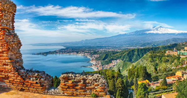 Ruinas del antiguo teatro griego en Taormina y el volcán Etna en t — Foto de Stock