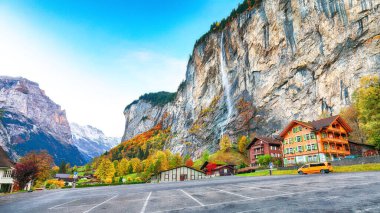 Arka planda muhteşem şelale Staubbach ve İsviçre Alpleri ile Lauterbrunnen köyünün göz kamaştırıcı sonbahar manzarası. Konum: Lauterbrunnen Köyü, Berner Oberland, İsviçre, Avrupa.