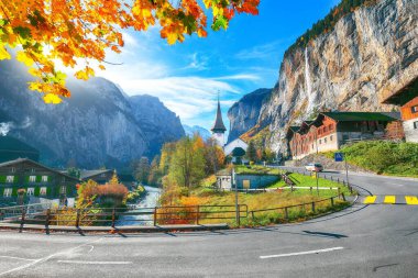Arka planda muhteşem şelale Staubbach ve İsviçre Alpleri ile Lauterbrunnen köyünün göz kamaştırıcı sonbahar manzarası. Konum: Lauterbrunnen Köyü, Berner Oberland, İsviçre, Avrupa.