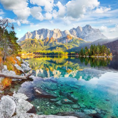 Zugspitze Zirvesi 'nin önündeki Eibsee Gölü' nün muhteşem sonbahar manzarası güneş ışığı altında. Konum: Eibsee Gölü, Garmisch-Partenkirchen, Bavyera Eyaleti, Almanya, Avrupa