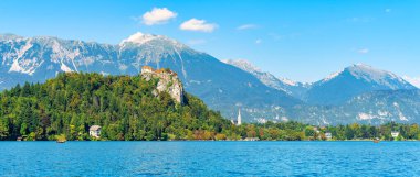 Nehir kıyısının panoramik manzarası yeşil bitki örtüsüyle kaplı, ve güneşli bir günde arka planda Alpler dağları, Slovenya