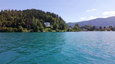 Nehir kıyısının panoramik manzarası yeşil bitki örtüsüyle kaplı, ve güneşli bir günde arka planda Alpler dağları, Slovenya