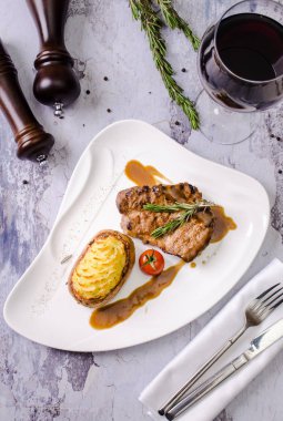 Üstten görünüm ızgara antrikot Biftek Biftek patates, sebze, taş tablo arka plan, restoran menü kavramı, ahşap tuz shaker ve biber üzerine bir bardak kırmızı şarap ile beyaz tabakta domates ile.